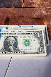 a stack of one dollar bills sitting on top of a table