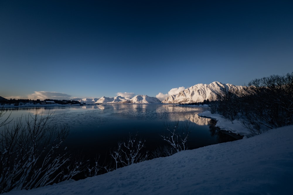 a body of water surrounded by snow covered mountains