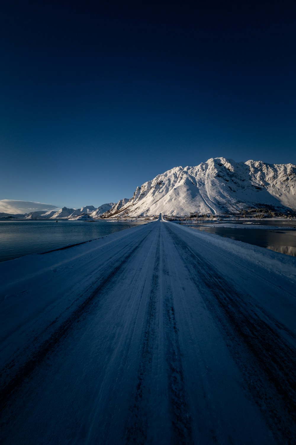 a snow covered road with a mountain in the background