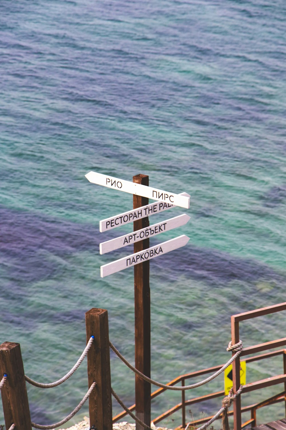 a street sign sitting on the side of a wooden railing