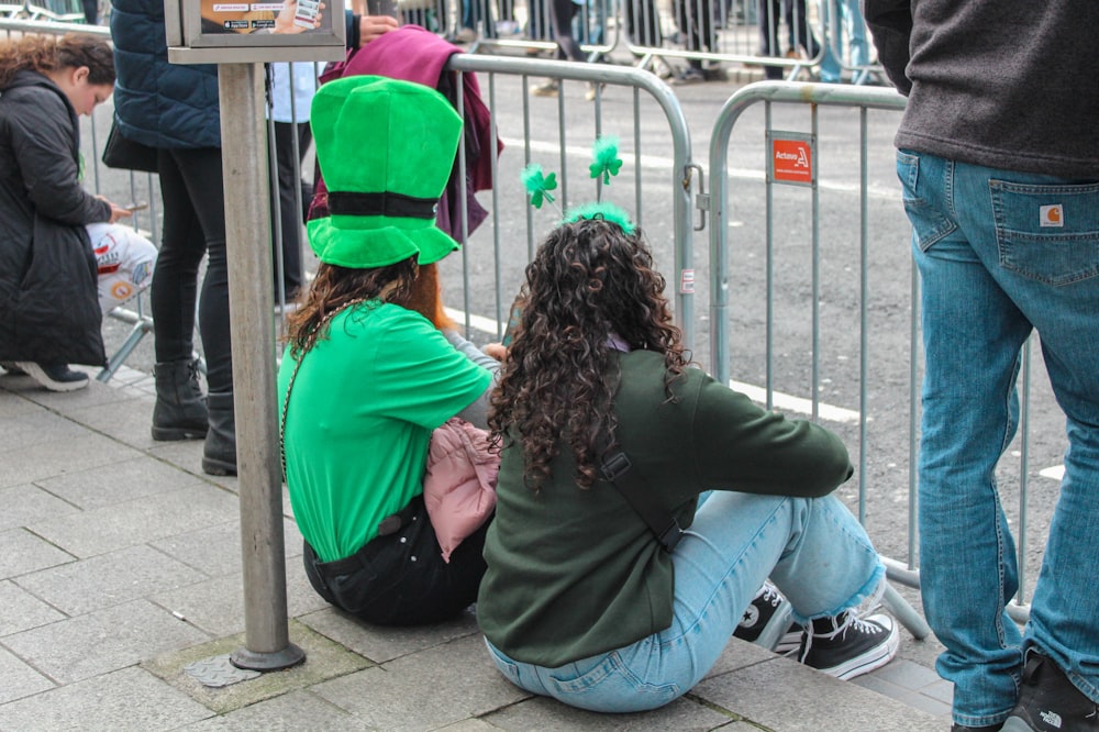 a group of people sitting next to a metal fence