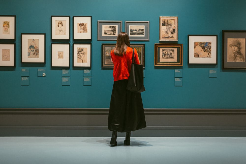 a woman standing in front of a wall with pictures on it