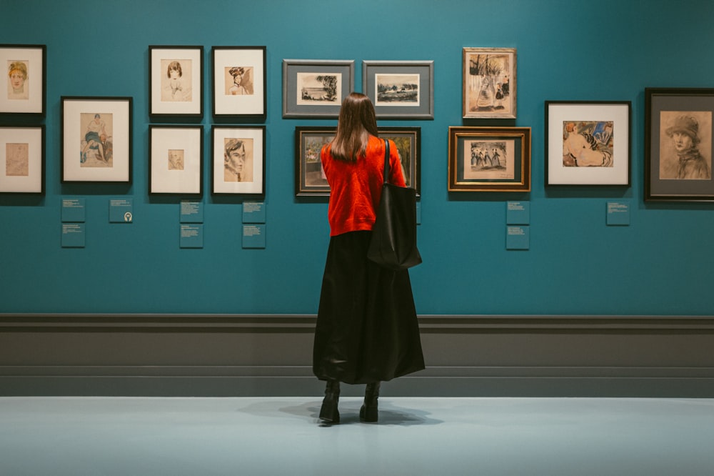 une femme debout devant un mur avec des images dessus