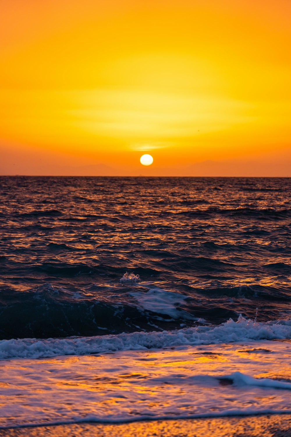 the sun is setting over the ocean with waves