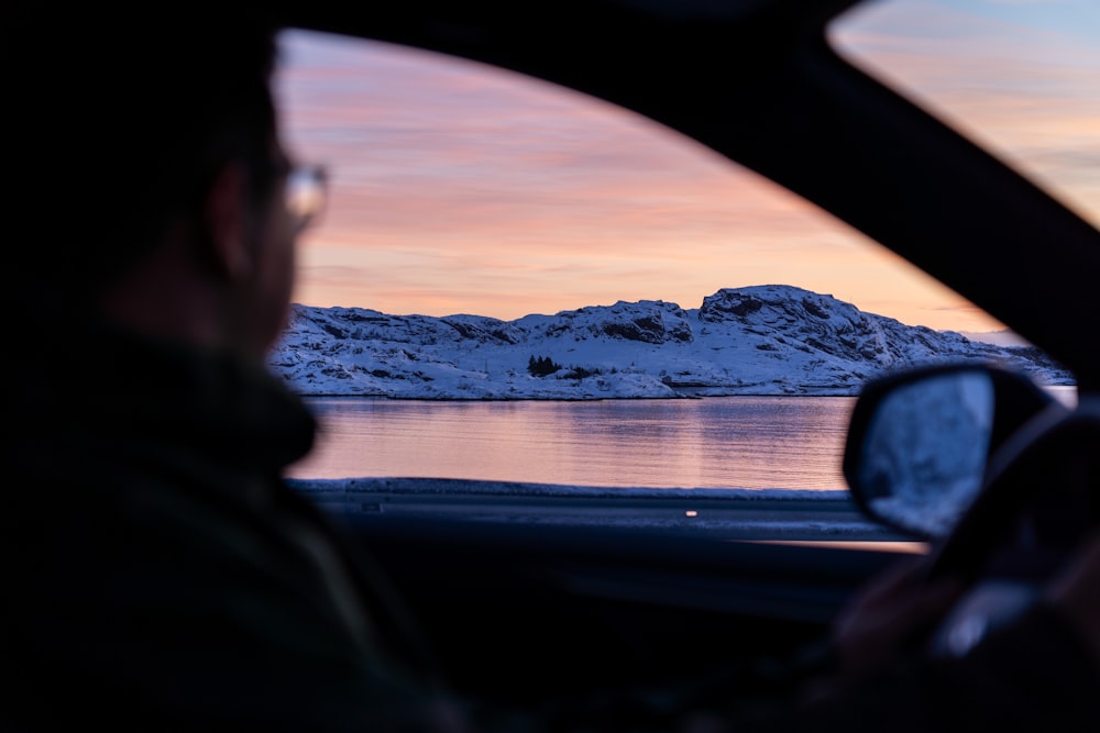 um homem dirigindo um carro em uma estrada nevada