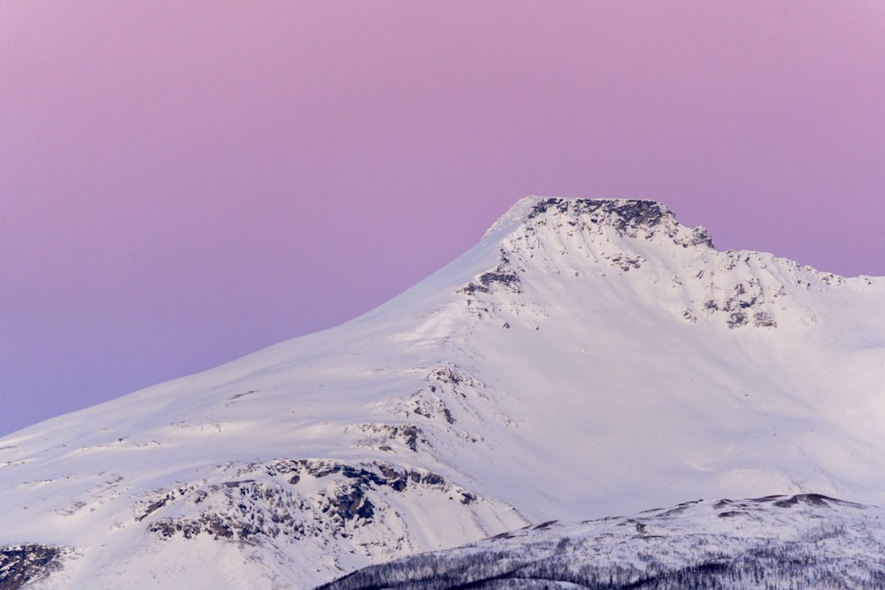 uma montanha coberta de neve com um céu rosa ao fundo