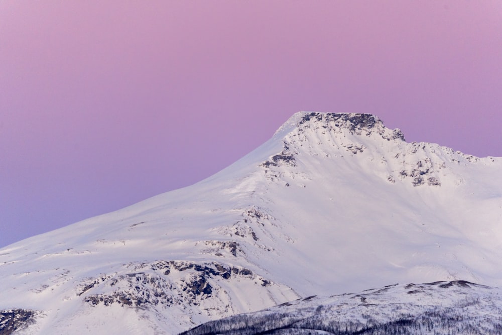 a snow covered mountain with a pink sky in the background