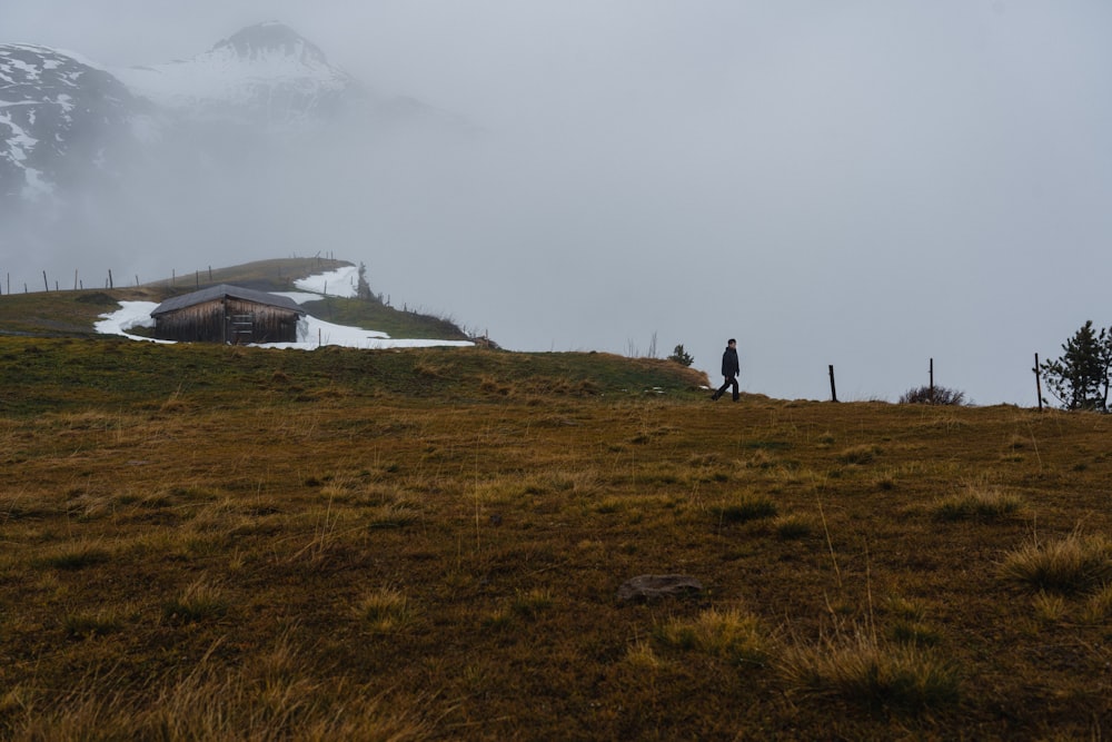 a man standing on top of a grass covered hillside