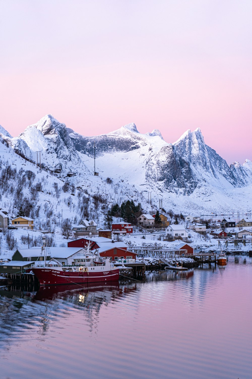 a boat is docked in the water in front of a snowy mountain