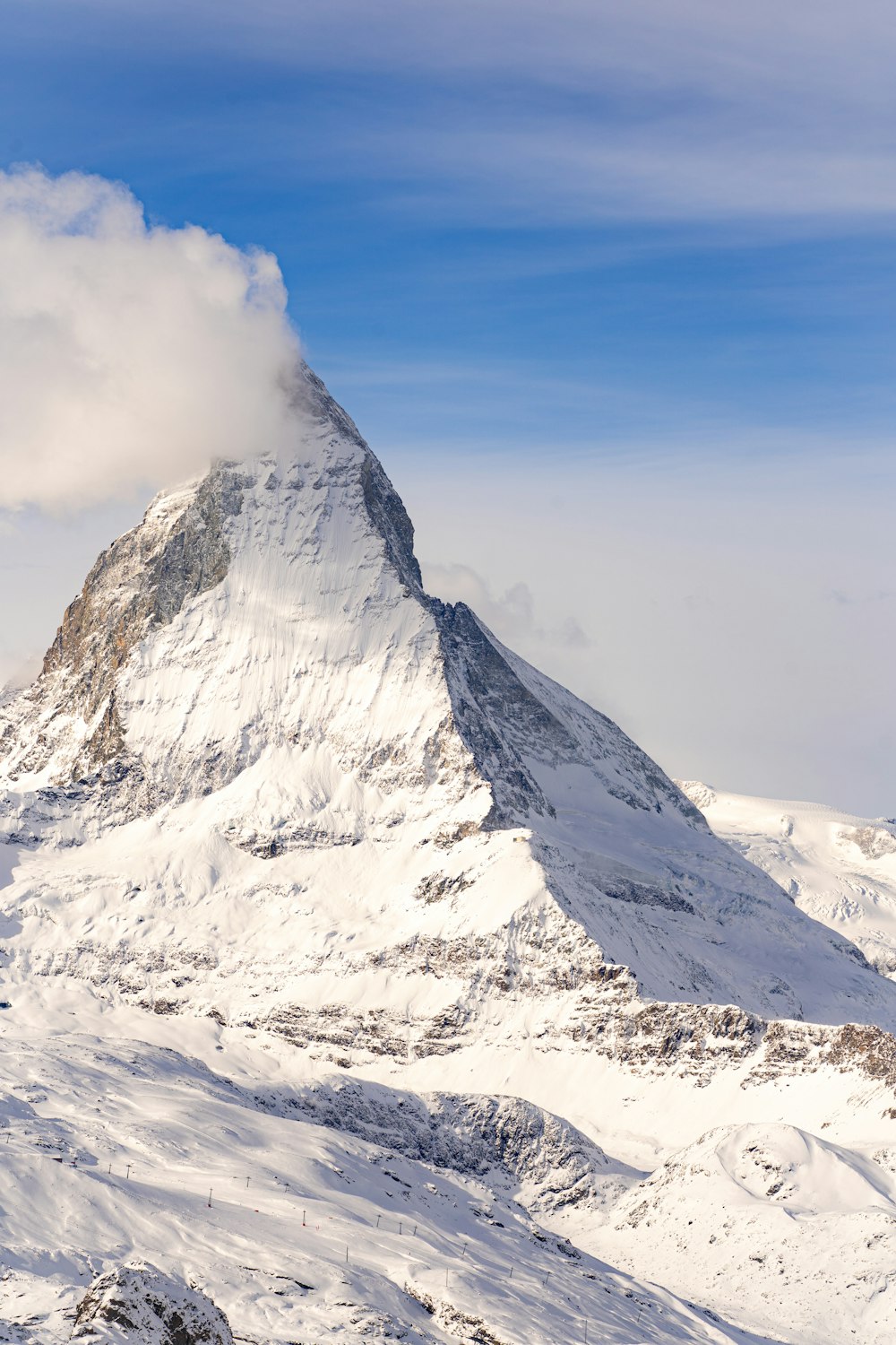 a snow covered mountain with a cloud in the sky