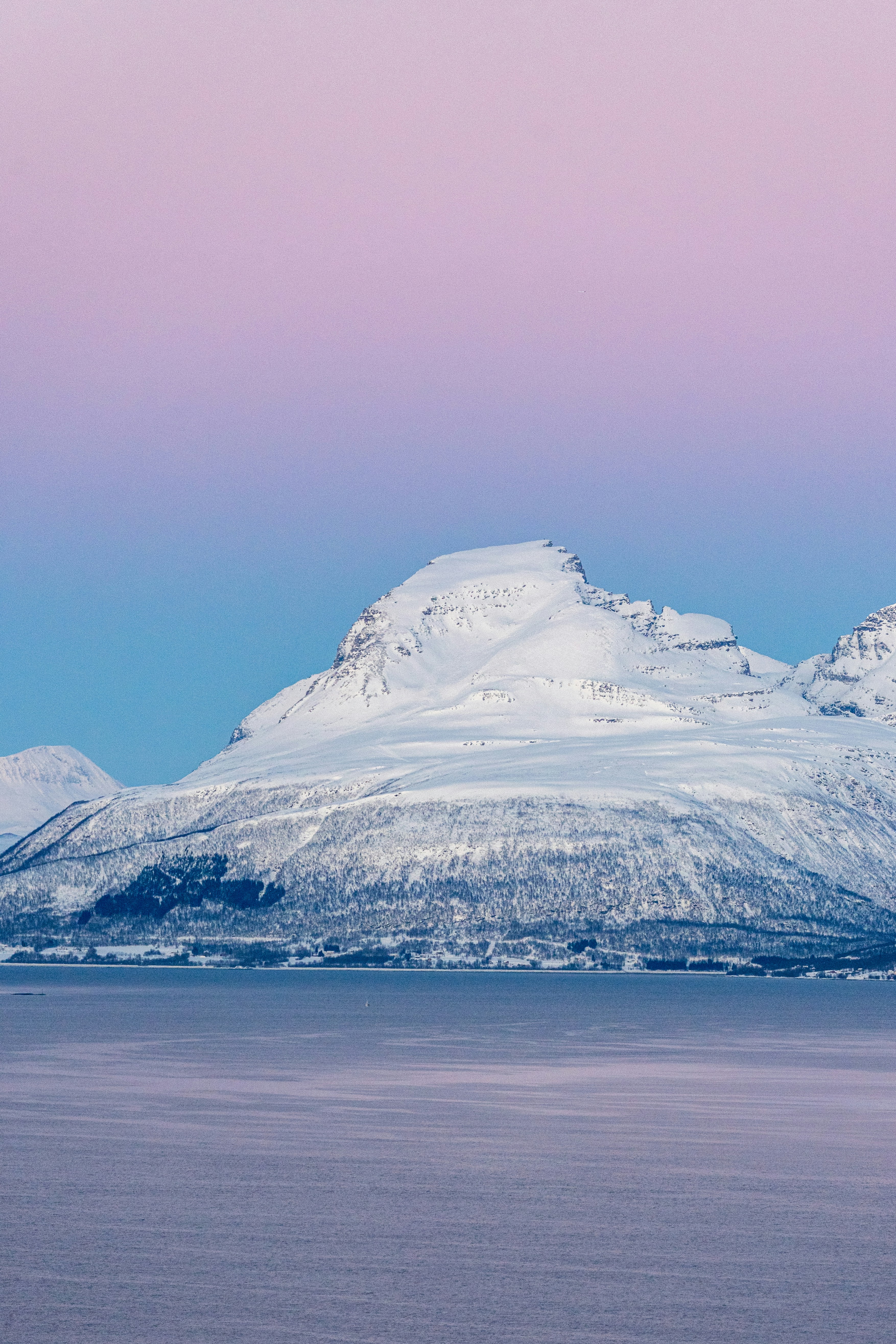 a large mountain covered in snow next to a body of water