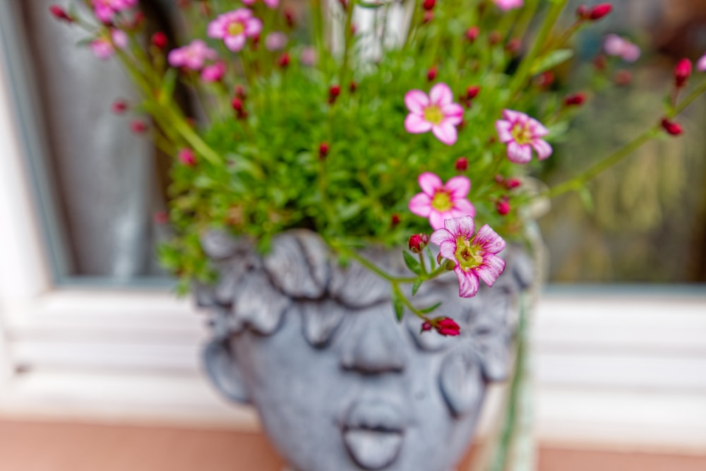 a vase filled with pink flowers sitting on top of a window sill