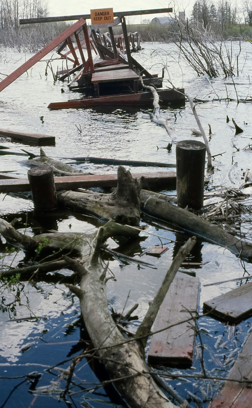 a flooded area with a wooden bridge and debris