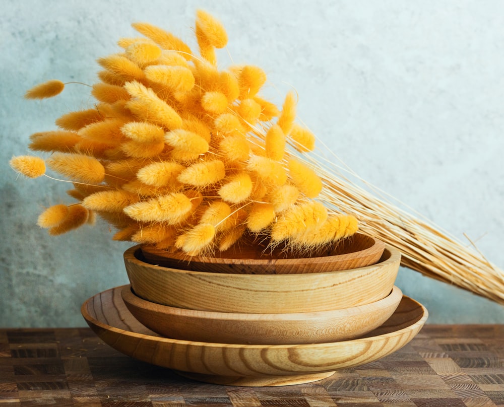 a wooden bowl filled with yellow flowers on top of a wooden table