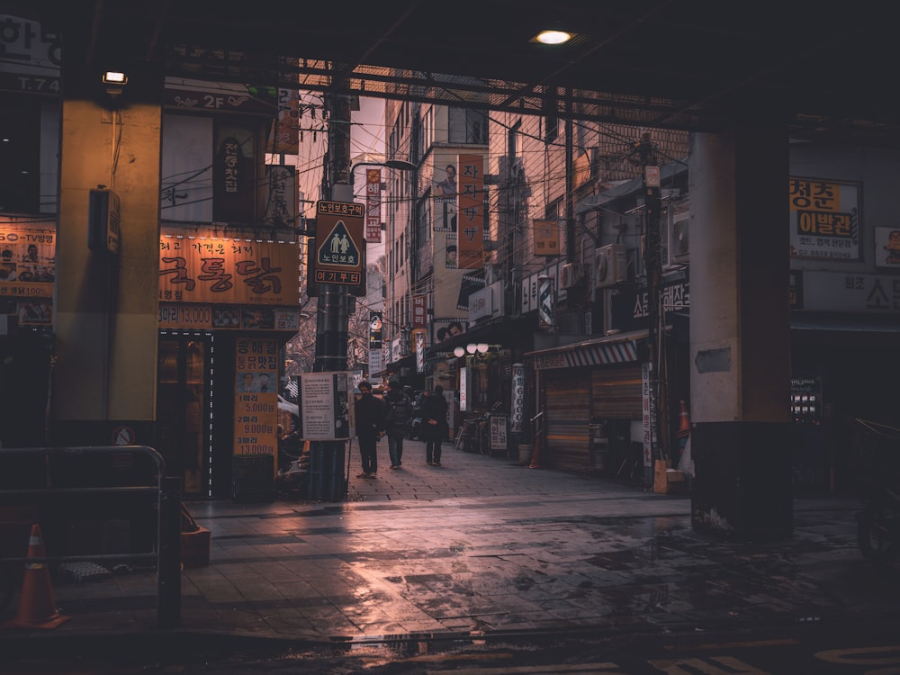 a city street at night with people walking on the sidewalk