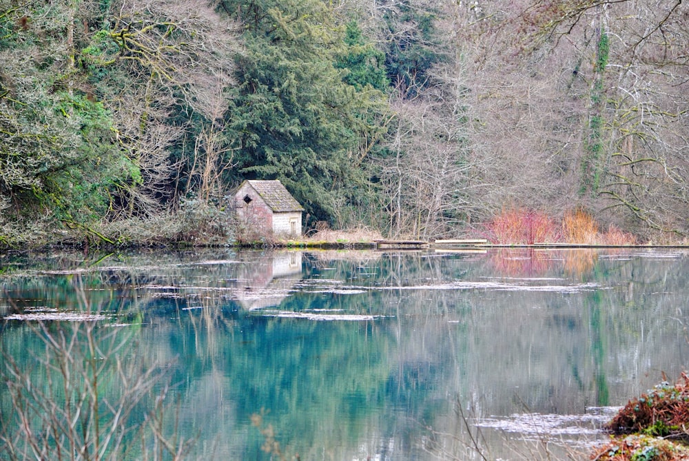 a small house sitting on top of a lake surrounded by trees