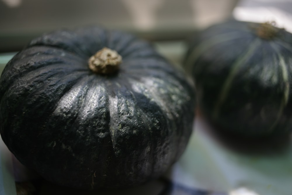 a close up of two black pumpkins on a table