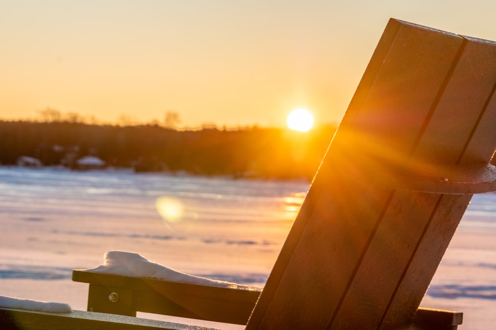 a wooden chair sitting on top of snow covered ground