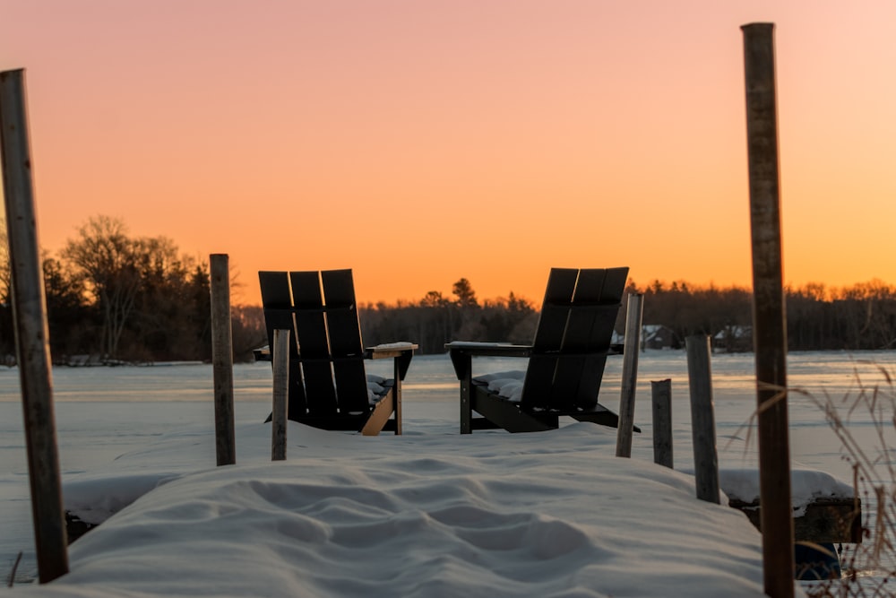 a couple of chairs sitting on top of a snow covered ground