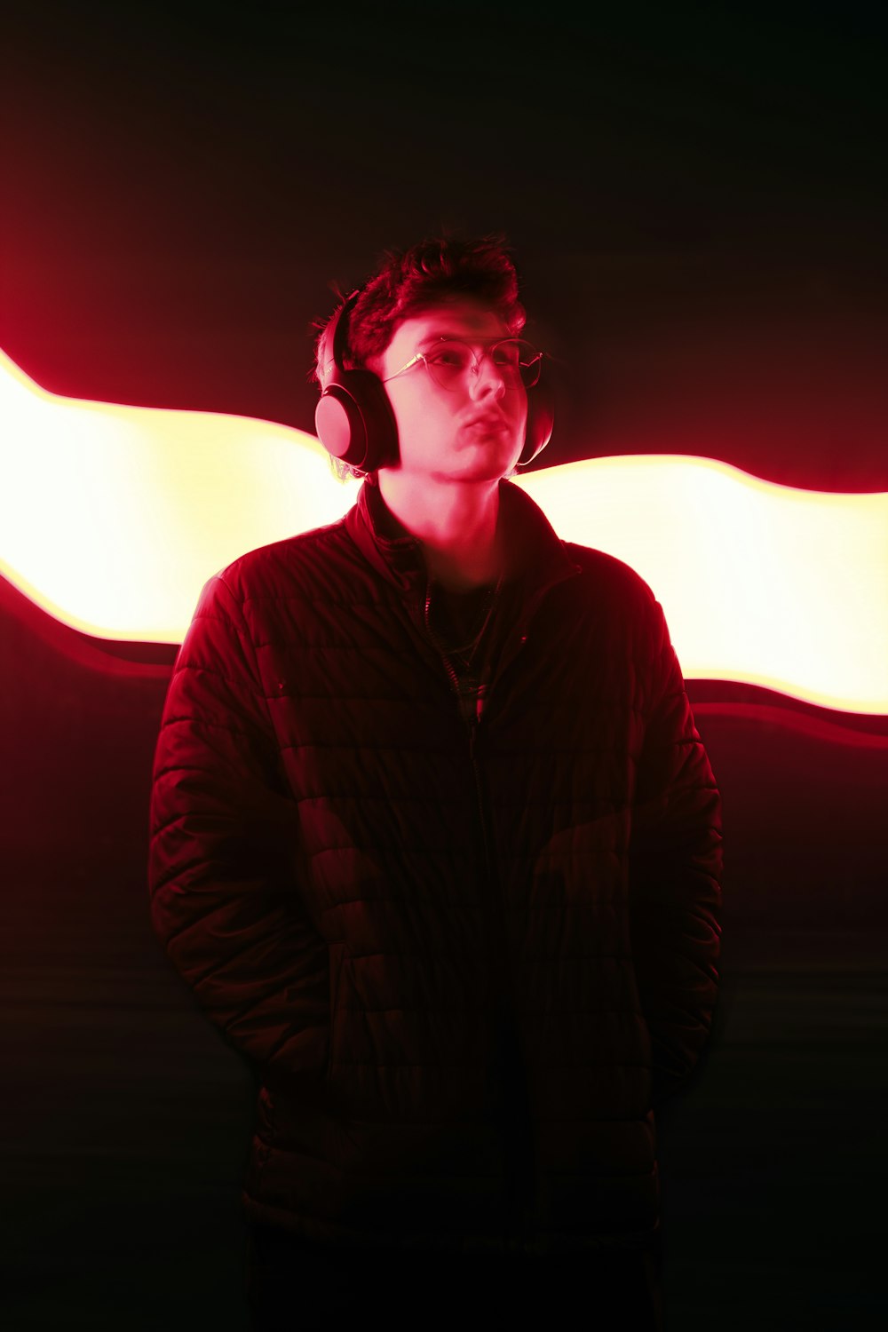 a man wearing headphones standing in front of a red light