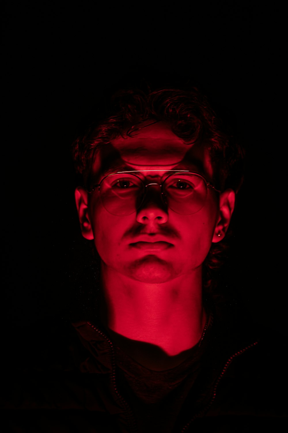 a man wearing glasses in the dark with a red light
