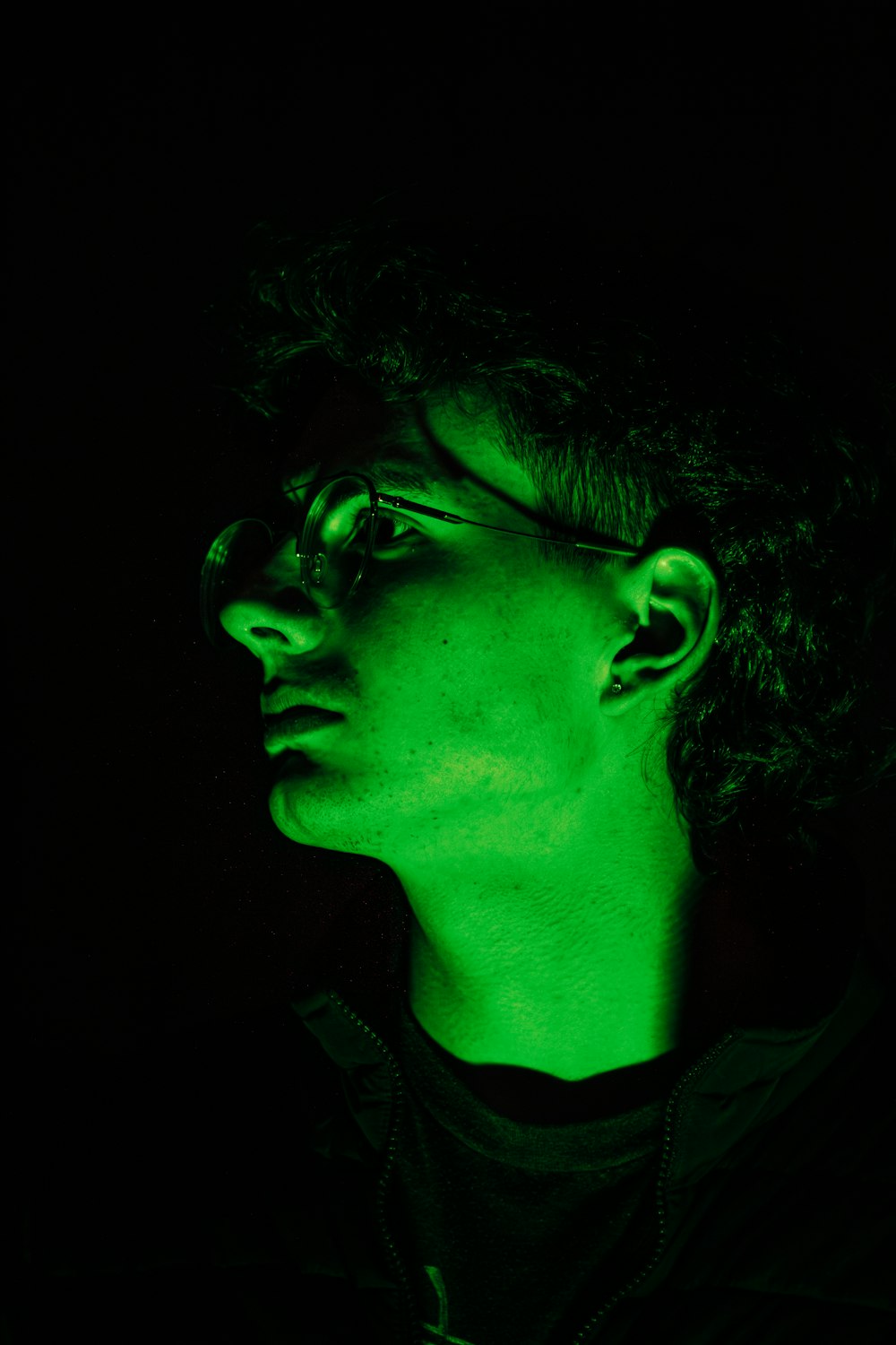 a man in a dark room with a green light on his face