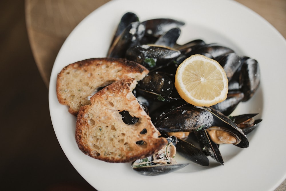 a white plate topped with mussels and a slice of lemon