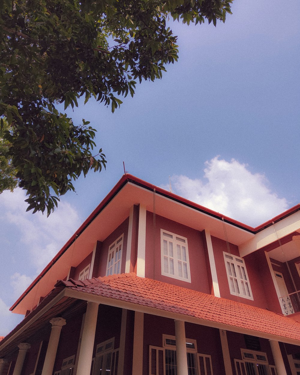 une maison rouge et blanche avec un arbre devant elle