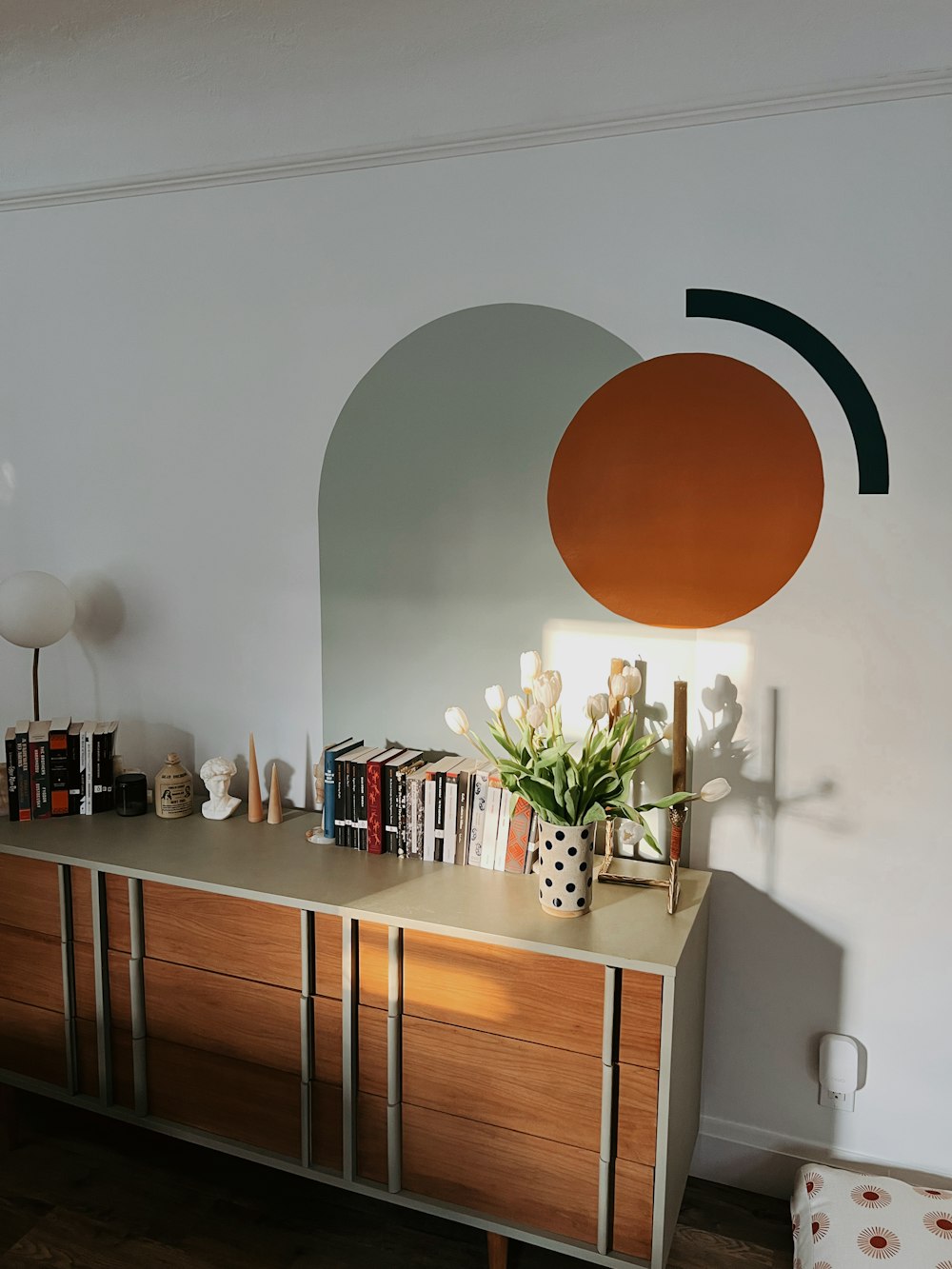 a room with a dresser and a lamp on the wall