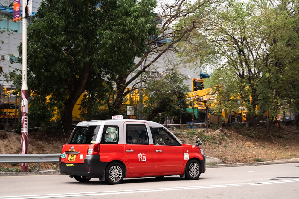 a red and white minivan driving down a street