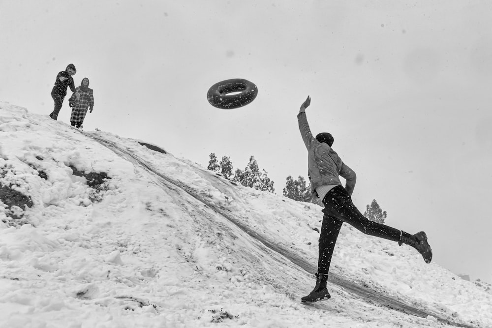 a black and white photo of people playing frisbee in the snow