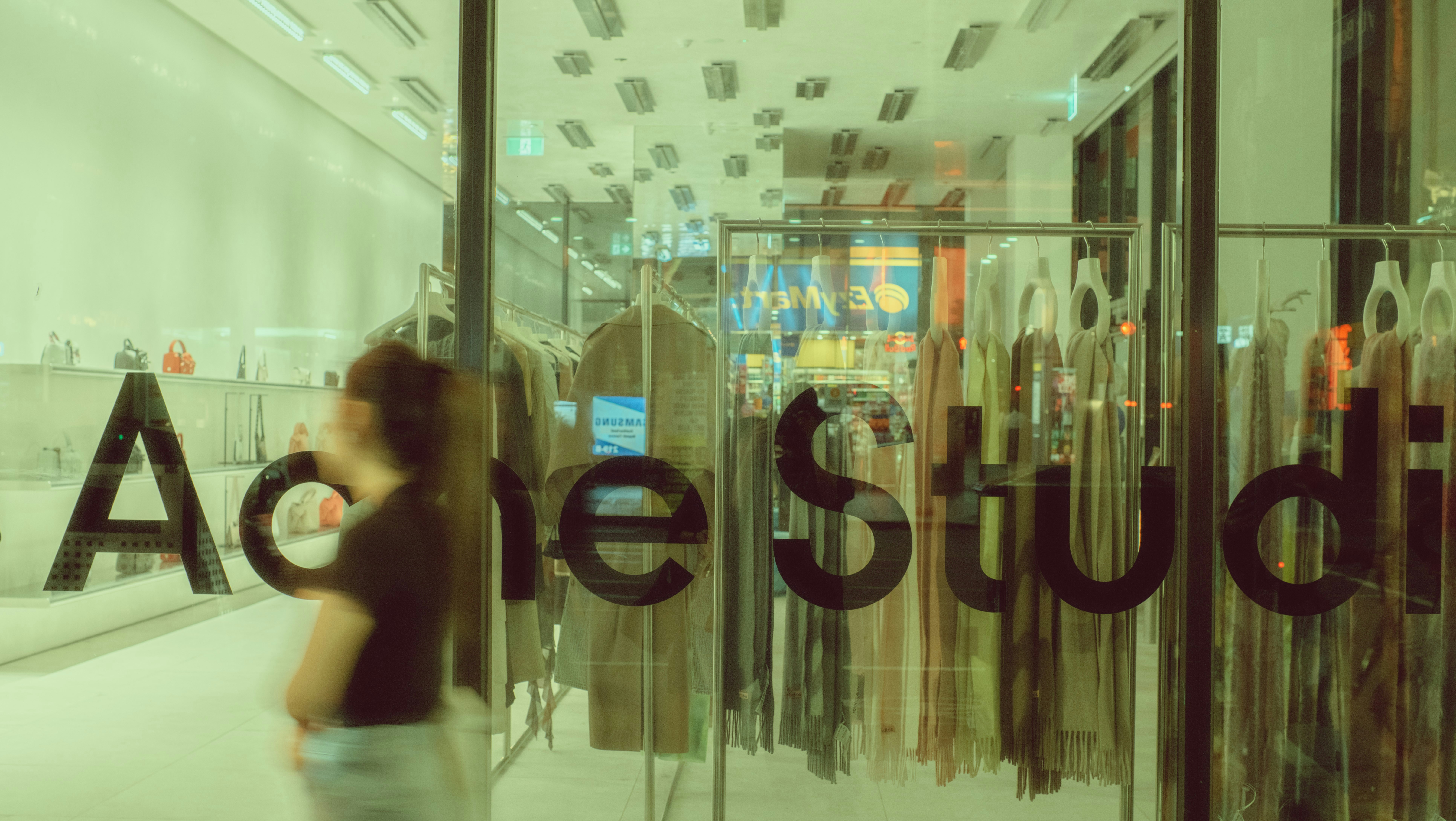 a woman walking past a glass window with a sign on it