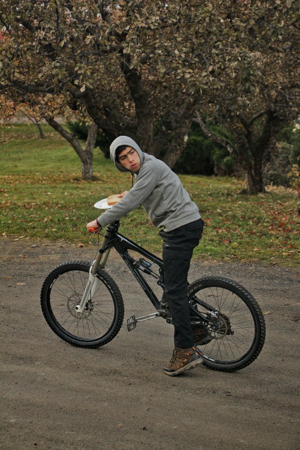 a young man riding a bike while holding a frisbee