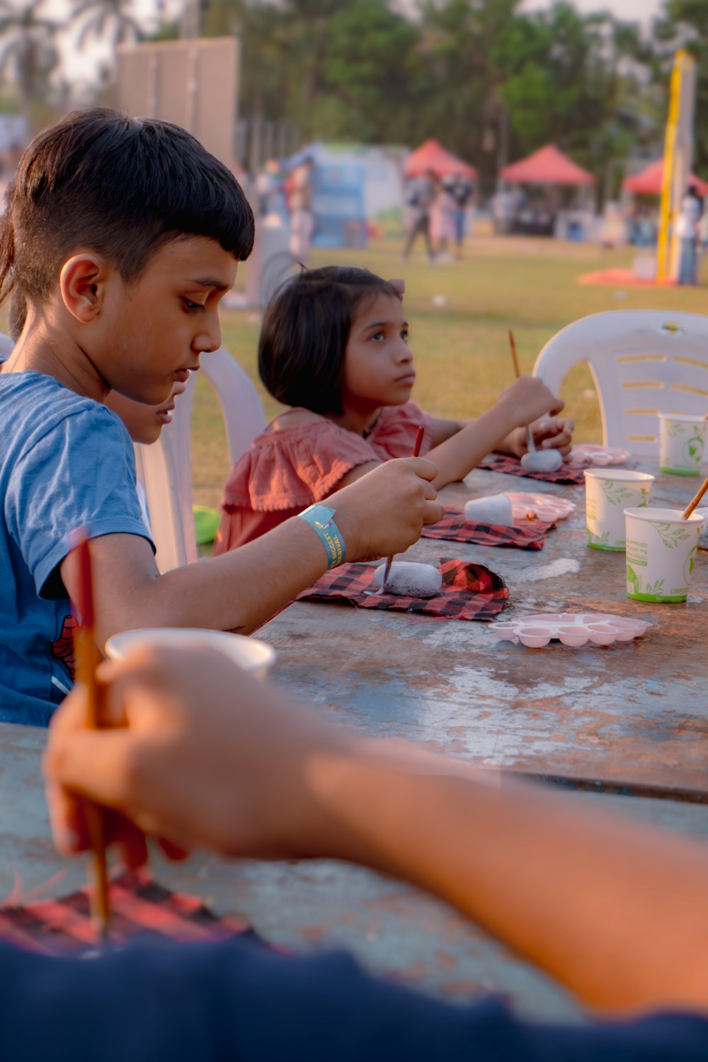 a group of children sitting at a table with paint