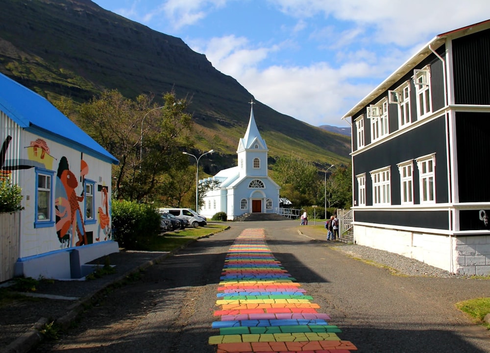 a rainbow painted street with a church in the background