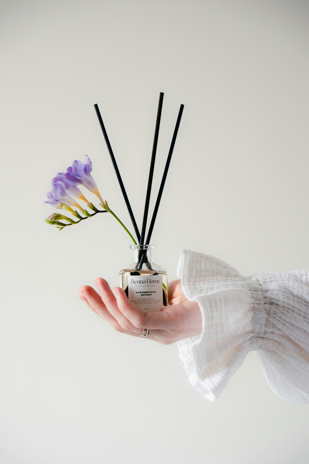 a hand holding a small bottle with flowers in it