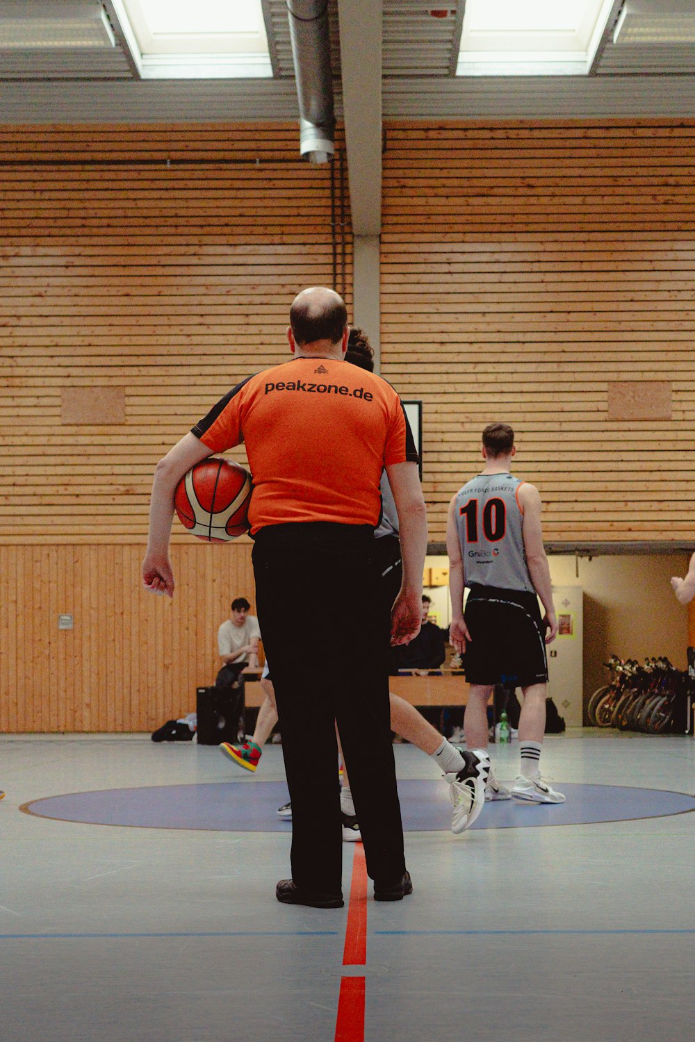 a man in an orange shirt is holding a basketball