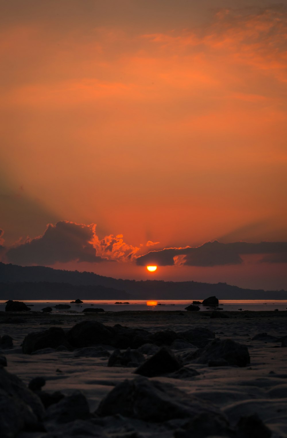 Il sole sta tramontando su una spiaggia rocciosa