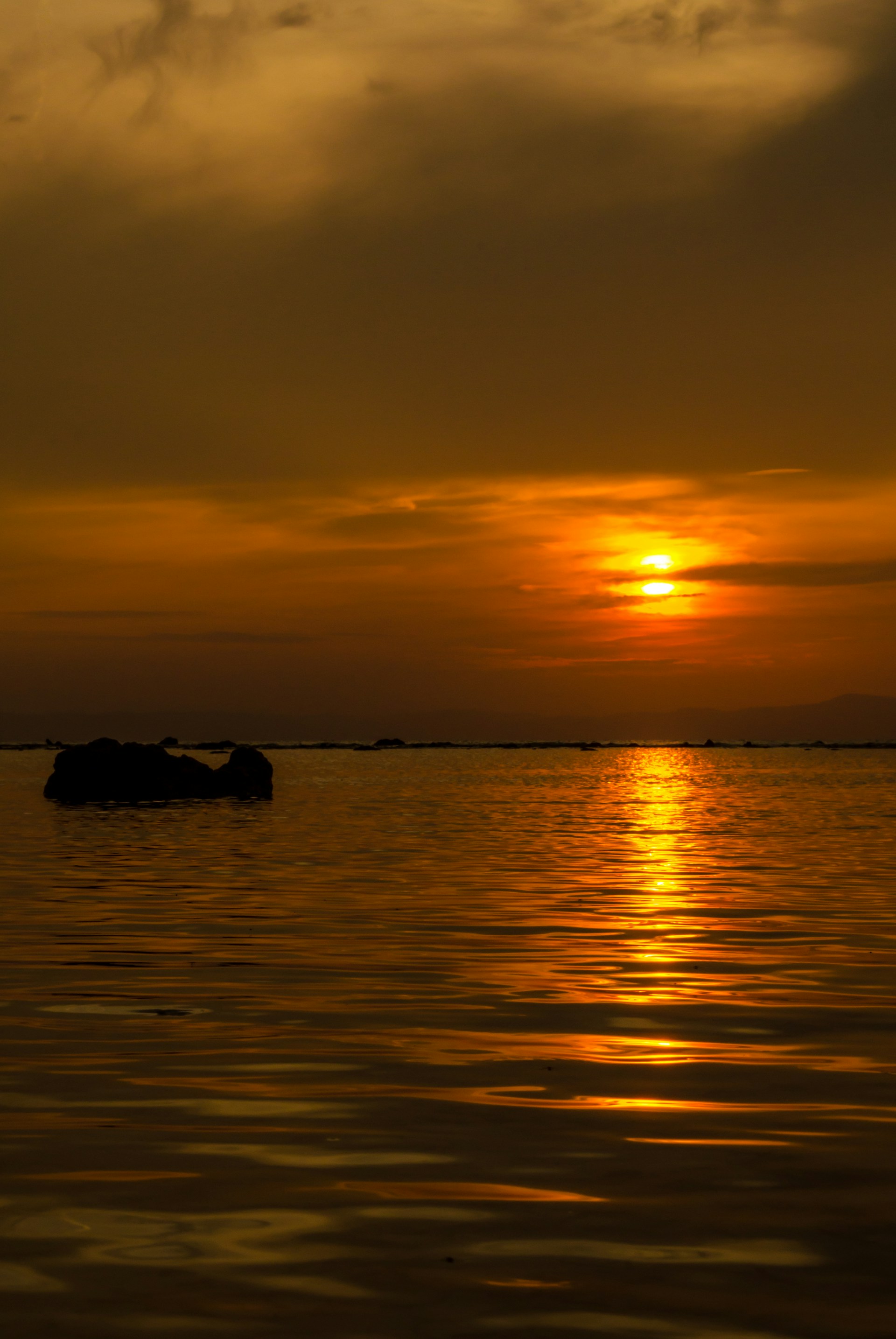 a large body of water with a sunset in the background