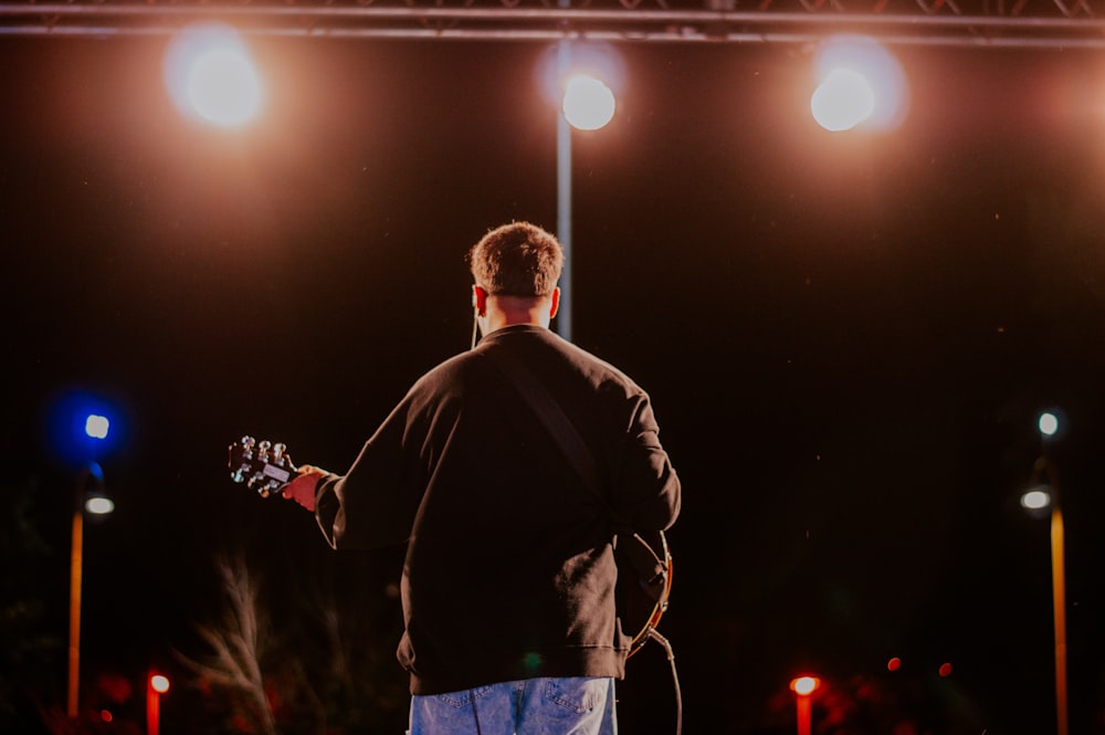 a man standing on a stage playing a guitar