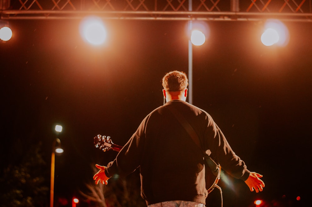 Un hombre parado en un escenario con una guitarra