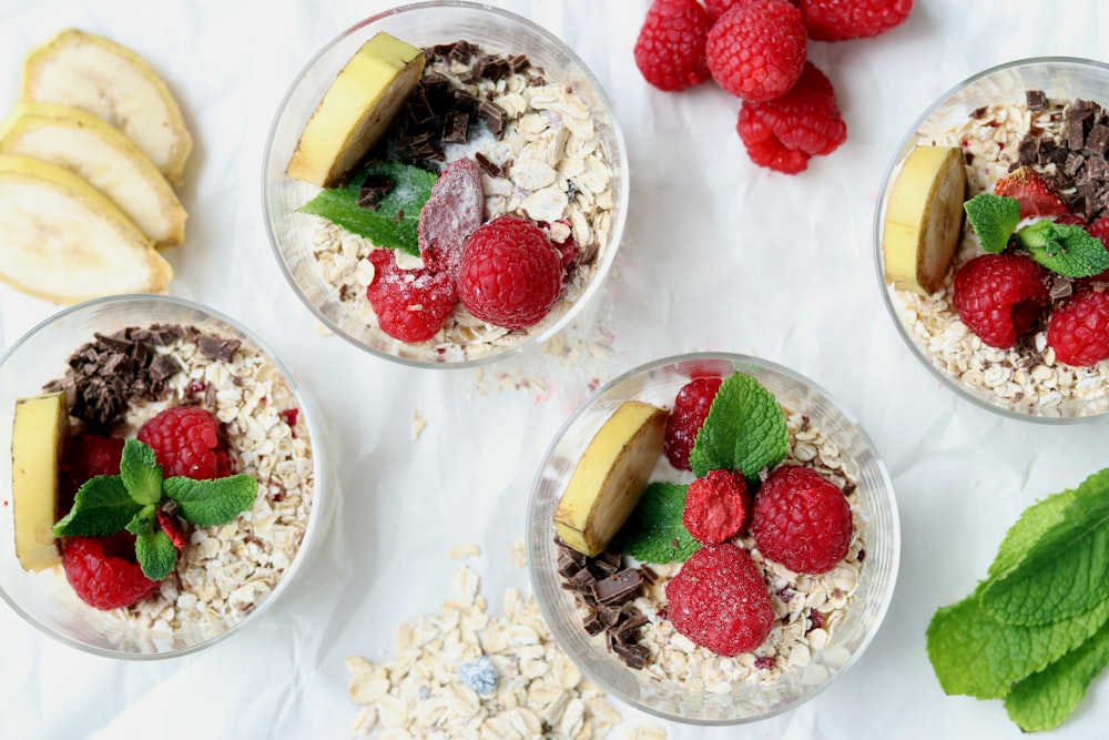 four glasses of oatmeal with raspberries and bananas