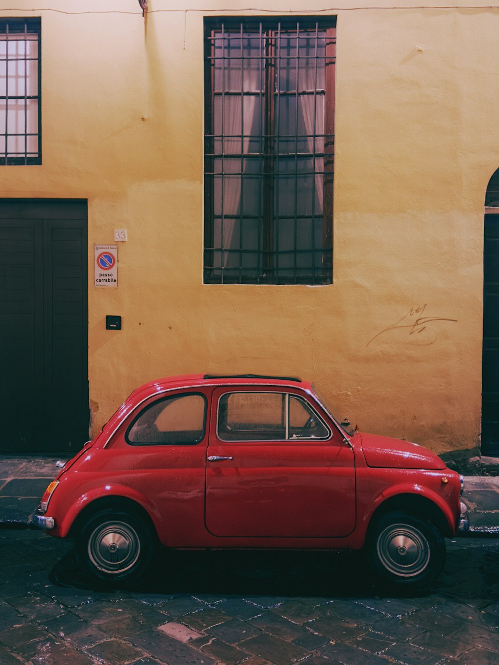 a red car parked in front of a yellow building