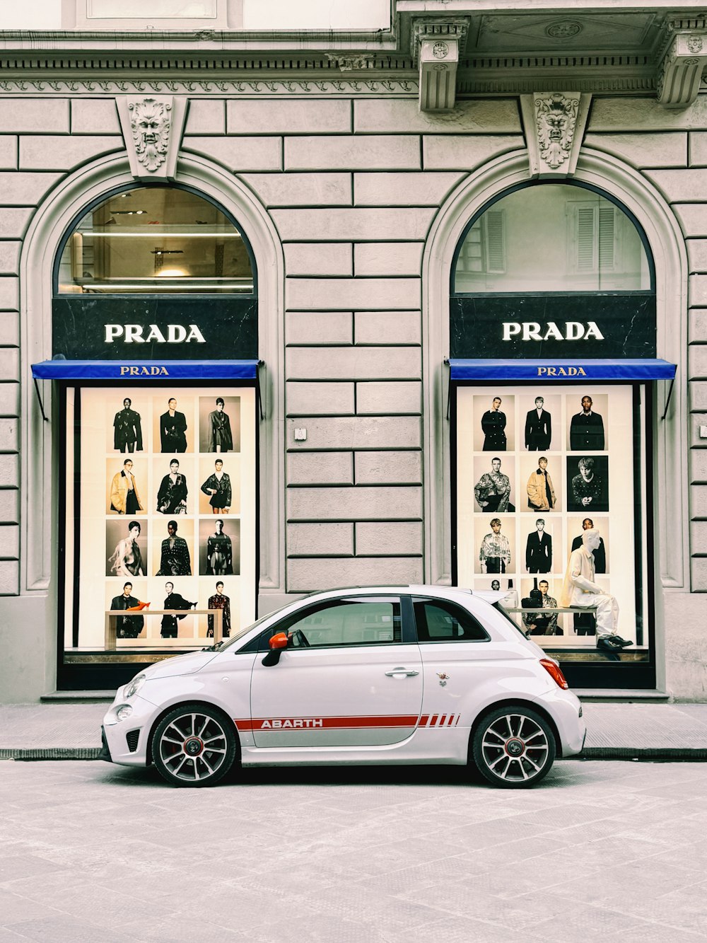 a white car parked in front of a prada store