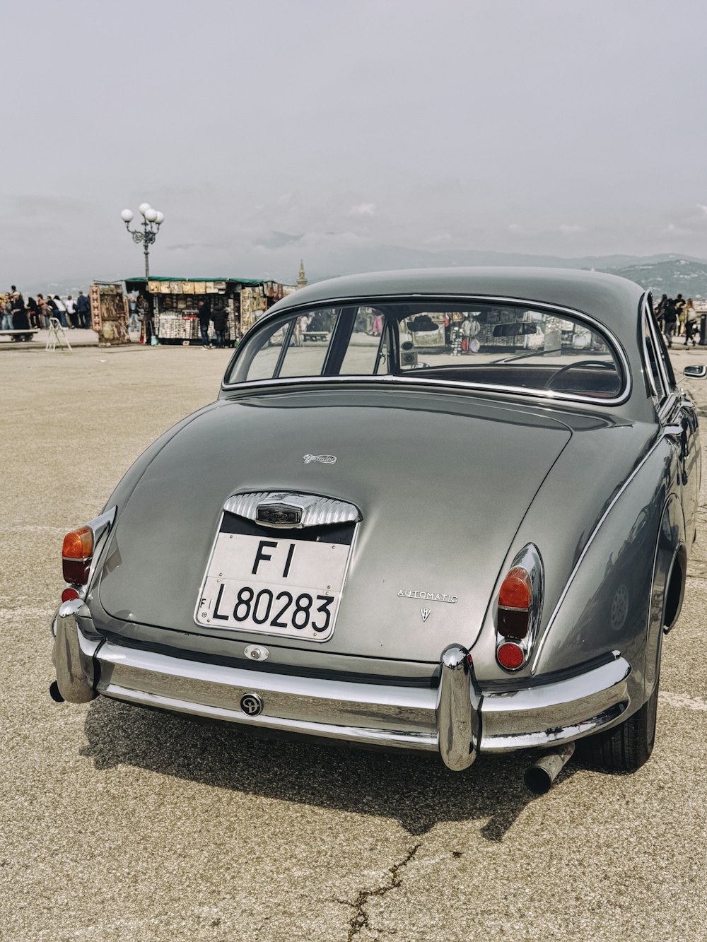 an old grey car parked in a parking lot