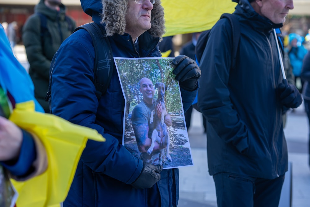 a woman holding a picture of a man in a hat