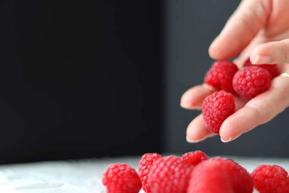 a person holding raspberries in their hand