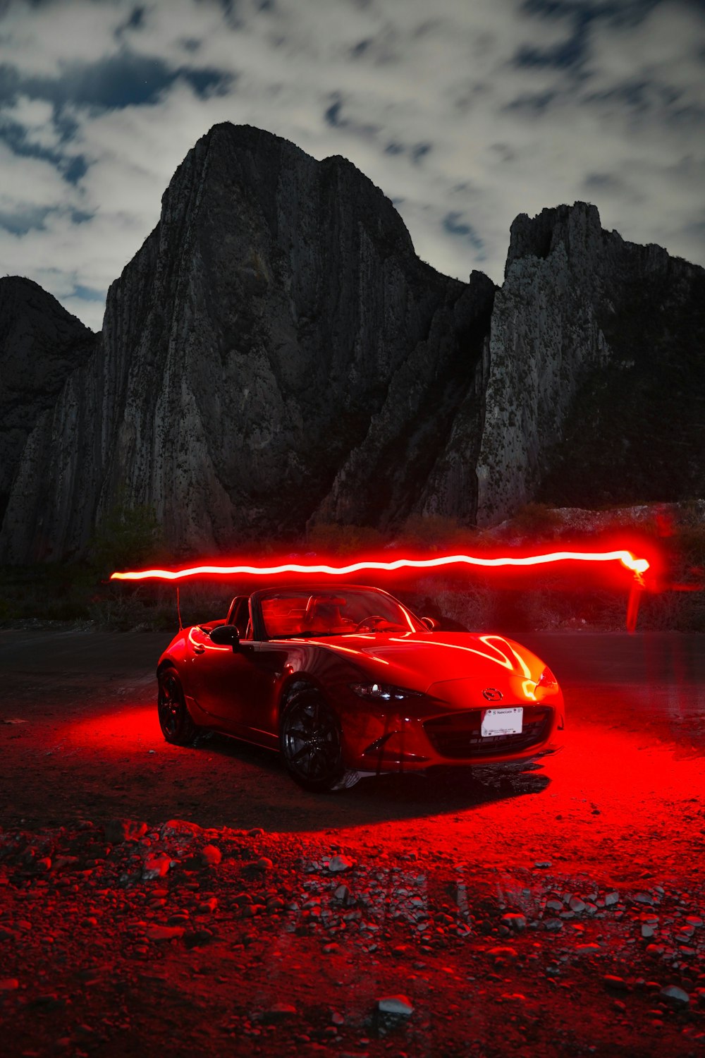 a red sports car parked in front of a mountain
