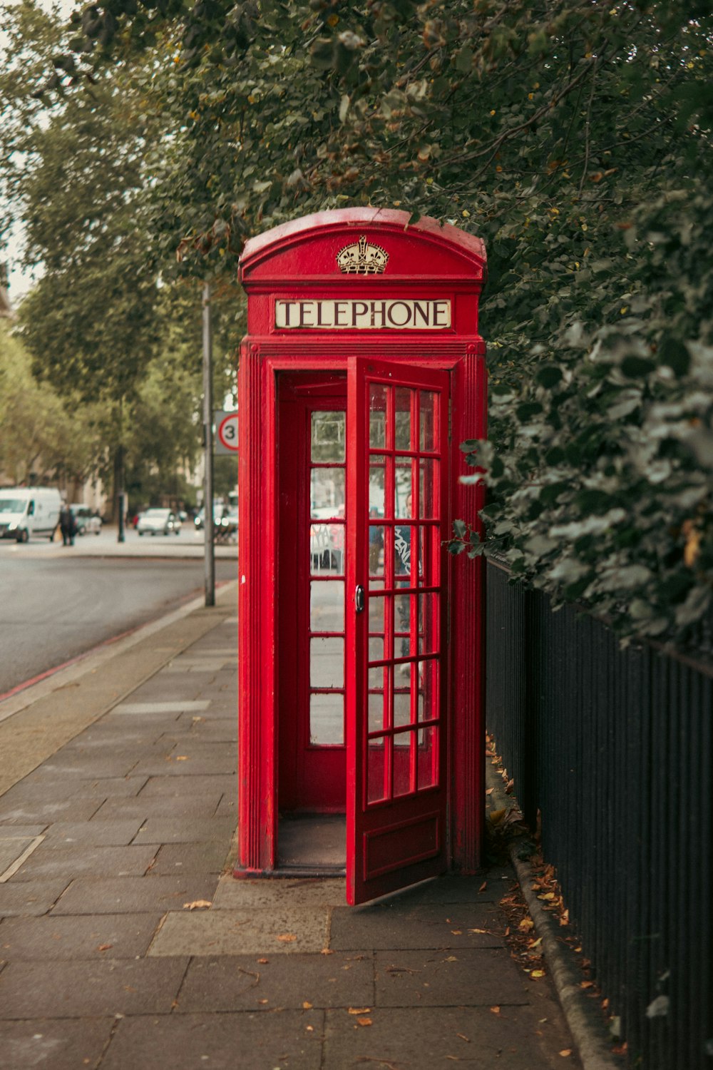 a red phone booth sitting on the side of a road