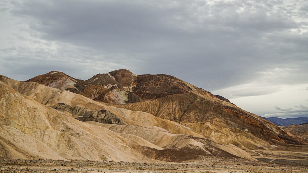 a group of mountains in the desert under a cloudy sky,